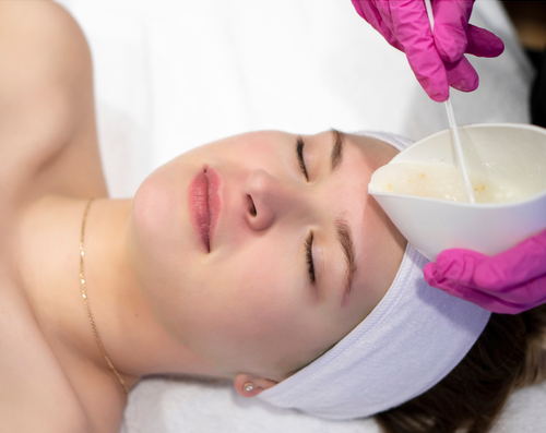 Woman laying down with eyes closed about to receive a facial treatment.
