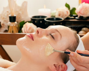 Esthetician applying serum to woman's face during facial