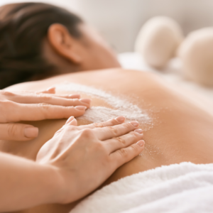 Esthetician applying a scrub to a woman's back.