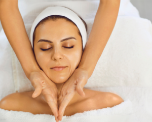 Esthetician massaging woman's face with both hands during flow and glow treatment