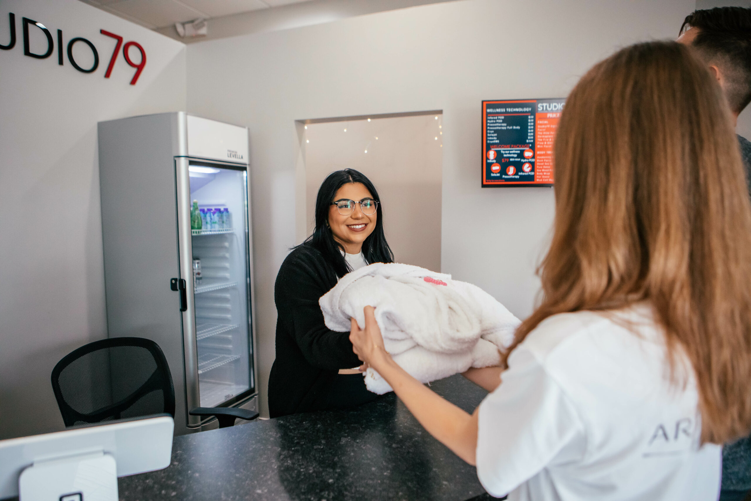 Kissimmee spa receptionist handing a robe to new customer.