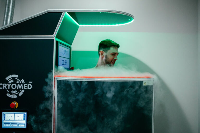 Man standing in the whole body cryotherapy chambers with smoke overflowing.